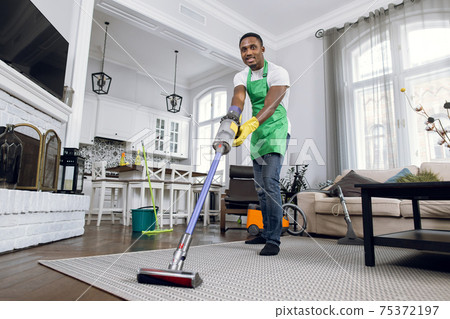 African man removing dust from carpet with vacuum cleaner African man removing dust from carpet with vacuum cleaner 75372197