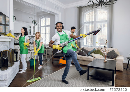 African cleaner dancing with vacuum at room. Joyful house cleaning. African cleaner dancing with vacuum at room. Joyful house cleaning. 75372220