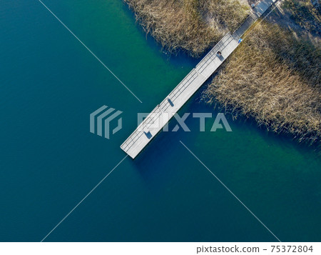 Aerial view of wood pier with fishers and their fishing rods at the Miramar lake, San Diego 75372804