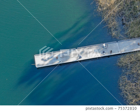 Aerial view of wood pier with fishers and their fishing rods at the Miramar lake, San Diego 75372810