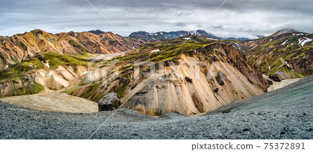 Beautiful panoramic Icelandic landscape of colorful rainbow volcanic Landmannalaugar mountains, at famous Laugavegur hiking trail with dramatic snowy sky, and red volcano soil in Iceland. 75372891