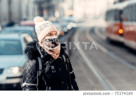 city streets with high traffic, cars and trams. woman with a mask on her face 75374184
