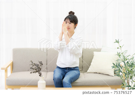 Young woman sitting on the sofa and making a request gesture Young woman sitting on the sofa and making a request gesture 75376527