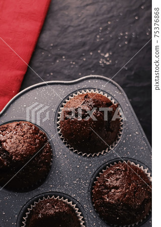 Just baked chocolate muffins in tray, homemade comfort food recipe Just baked chocolate muffins in tray, homemade comfort food recipe 75376868