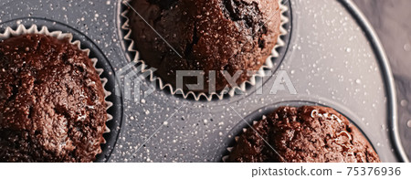 Just baked chocolate muffins in tray, homemade comfort food recipe 75376936