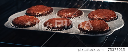 Chocolate muffins baking in the oven, homemade comfort food recipe 75377015