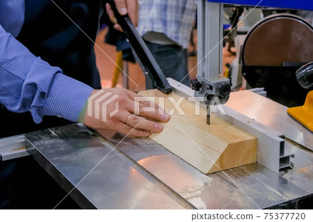 Carpenter using bandsaw tool, cutting piece of wood at workshop - close up Carpenter using bandsaw tool, cutting piece of wood at workshop - close up 75377720