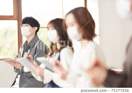 Seminar students wearing masks to take notes on tablets 75377856