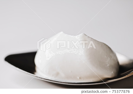 Thick white cream on golden spoon 75377876