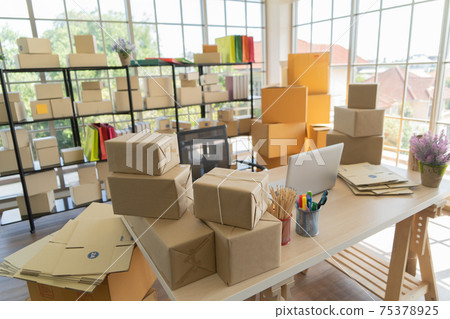 Interior of Postal parcel packaging carton box delivery and computer notebook laptop on table in working room, selling products online business. Shipping service. Retail shop at home office. Interior of Postal parcel packaging carton box delivery and computer notebook laptop on table in working room, selling products online business. Shipping service. Retail shop at home office. 75378925