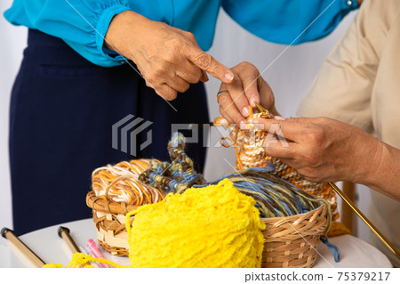Happy senior elder woman teaching knitting woven craft other old female mature togehter 75379217