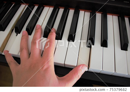 Left hand playing the electronic piano 75379682