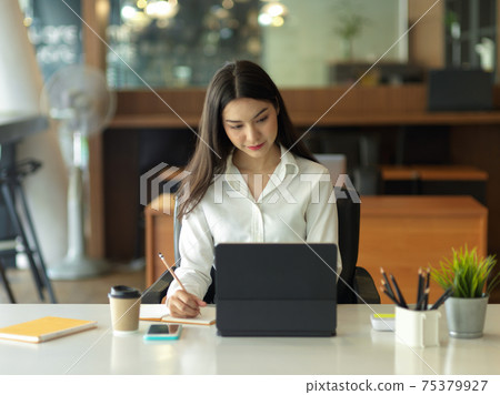 Businesswoman focusing on her work with digital tablet on office desk 75379927