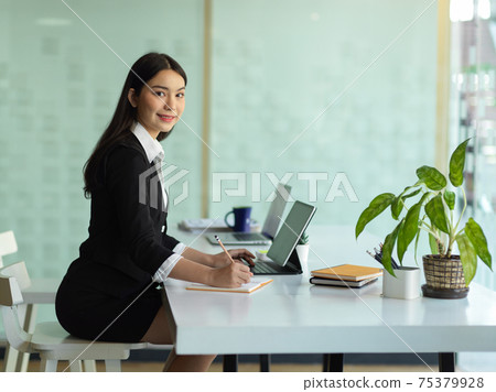 Female worker smiling to camera while working with office supplies in office room 75379928