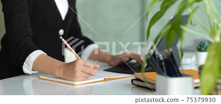 Businesswoman hand writing on schedule book on office table with office supplies 75379930