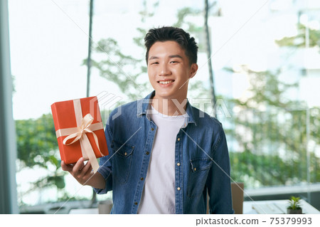 present box with gold ribbons standing on the table in hands present box with gold ribbons standing on the table in hands 75379993