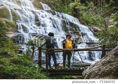 couples travel relax to photograph the waterfalls beautiful. In the winter. at the waterfall couples travel relax to photograph the waterfalls beautiful. In the winter. at the waterfall 75380035