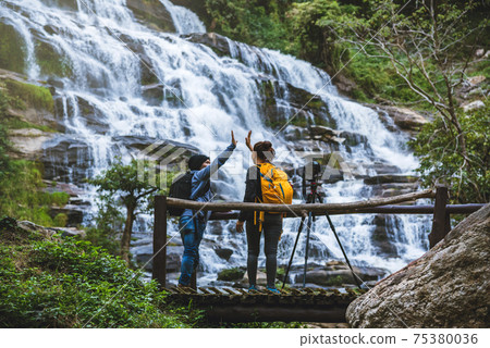 couples travel relax to photograph the waterfalls beautiful. In the winter. at the waterfall 75380036