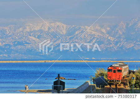 [Toyama Prefecture] Tateyama mountain range and train on the Amaharashi coast under fine weather 75380317