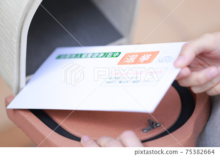 A woman's hand taking an election envelope from her mailbox 75382664