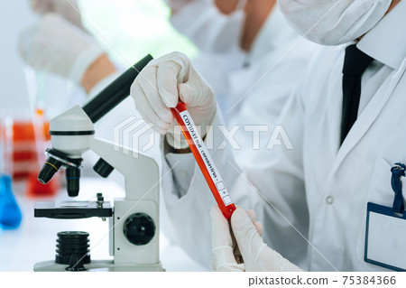 tube with the test for coronavirus in the hands of the scientist . 75384366