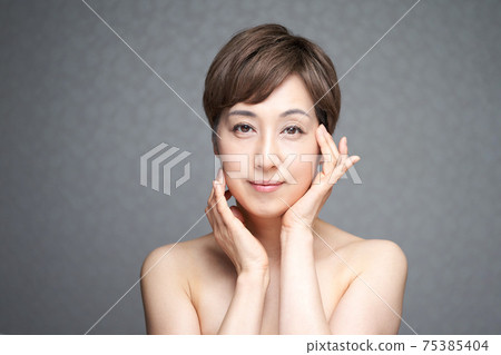 A middle-aged Japanese woman checking the moisture of her face with both hands 75385404