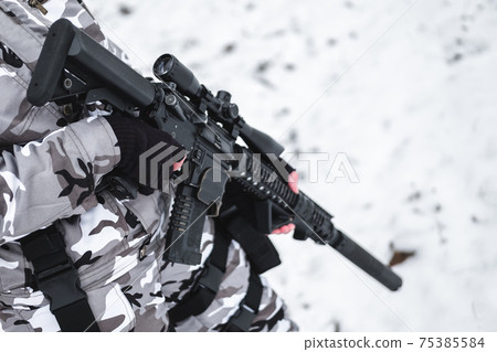 A military man in camouflage in the winter with a rifle patrols. 75385584