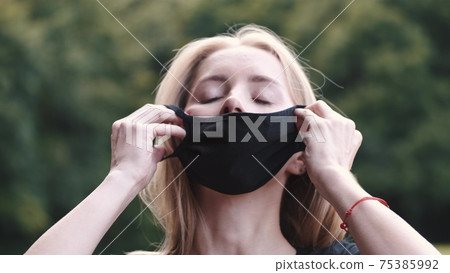 Beautiful girl puts a mask on her face on the nature Beautiful girl puts a mask on her face on the nature 75385992