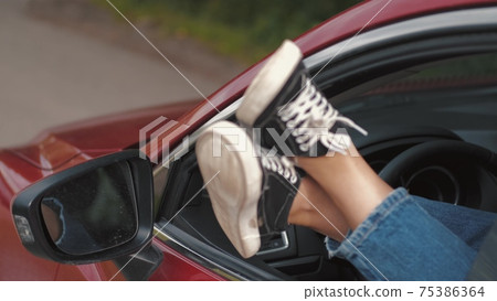 Cropped image of female feet out of car window Cropped image of female feet out of car window 75386364