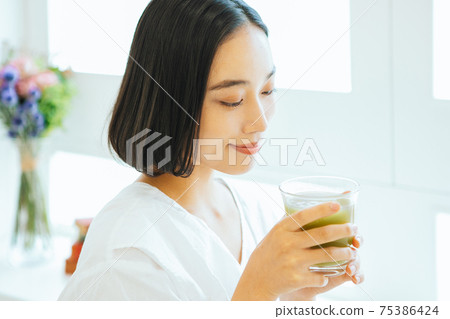 A woman drinking a green smoothie 75386424