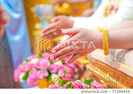 Water pouring ceremony, the closing of the bride's hand that is blessing pouring water using the conch shell. Traditional Thai wedding. Water pouring ceremony, the closing of the bride's hand that is blessing pouring water using the conch shell. Traditional Thai wedding. 75386456