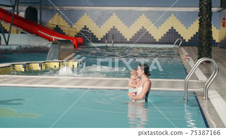 Mother with baby son going into indoor swimming pool 75387166