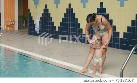 Mother with baby son going into indoor swimming pool 75387167