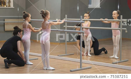 Young teacher teach little ballerinas on a dance class in studio 75387251