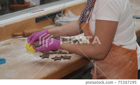 Woman cutting chocolate shortcrust dough for cookies Woman cutting chocolate shortcrust dough for cookies 75387295
