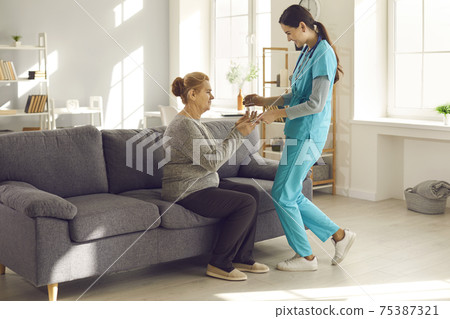 Friendly nurse at hospital or assisted living facility giving glass of water to mature woman 75387321