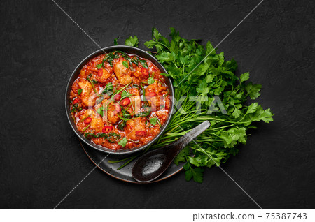 Chicken Vindaloo with spinach in black bowl on dark slate table top. Indian cuisine meat curry dish 75387743