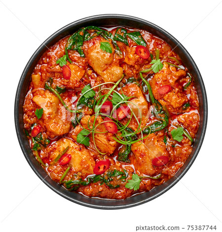 Chicken Vindaloo with spinach in black bowl isolated on white. Indian cuisine meat chilli curry dish 75387744