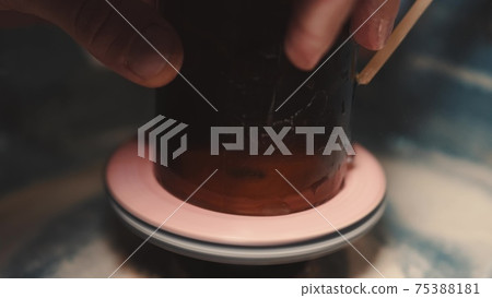 Crafts man is polishing dark glass in a special machine 75388181