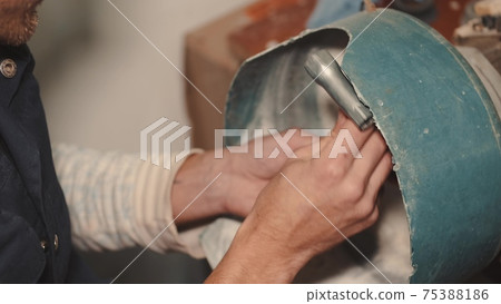Crafts man is polishing dark glass in a special machine 75388186