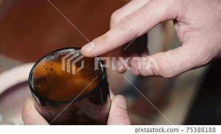 Crafts man is polishing dark glass in a special machine 75388188