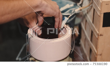 Crafts man is polishing dark glass in a special machine 75388190