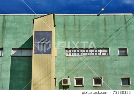 Green facade of an industrial building against the sky 75388333