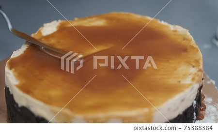 Female chef is working on cake, standing at table in kitchen 75388384