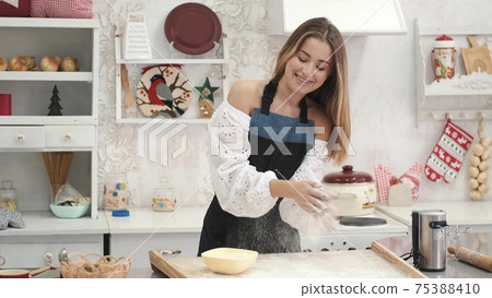 Pretty European woman having fun with flour in kitchen 75388410