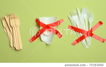 plastic forks and spoons glued with red tape on a green background, avoiding plastic plastic forks and spoons glued with red tape on a green background, avoiding plastic 75391600