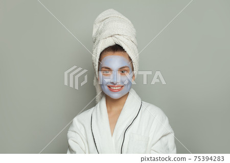 Beautiful young woman in cosmetic face mask. Facial treatment and skin care concept 75394283