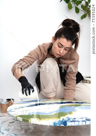 A young woman creates a painting using liquid art technique 75395824