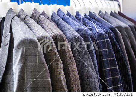men's jackets in check and stripes hang on hangers in the atelier 75397131
