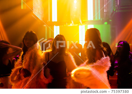 Silhouette image of people dance in disco night club to music from DJ on stage 75397380